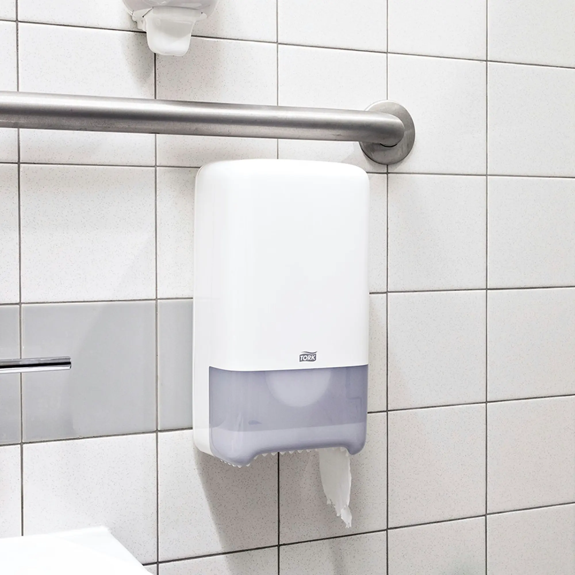 Tork Mid-size papier toaletowy, biały dozownik ścienny zamontowany w łazience